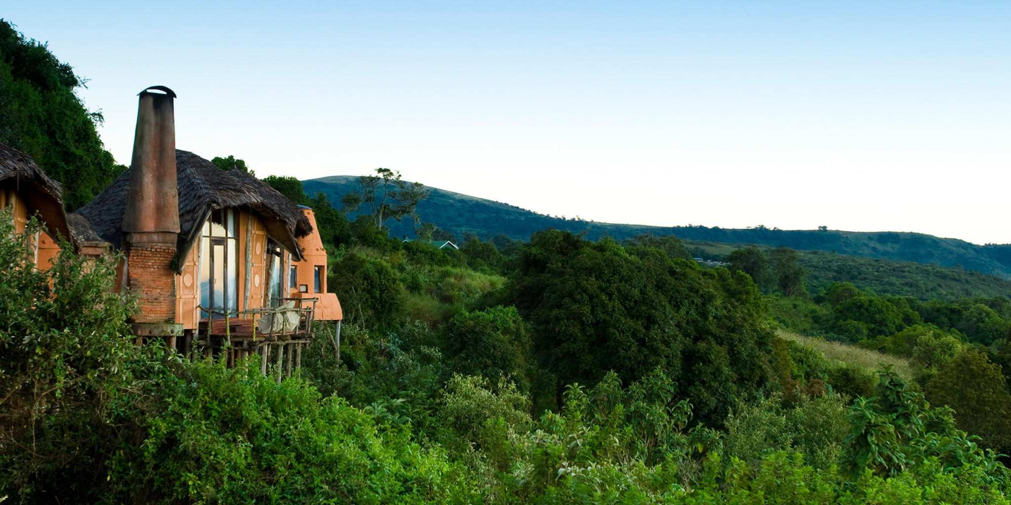 Outside view of Ngorongoro Crater Lodge surrounded by lush greenery.