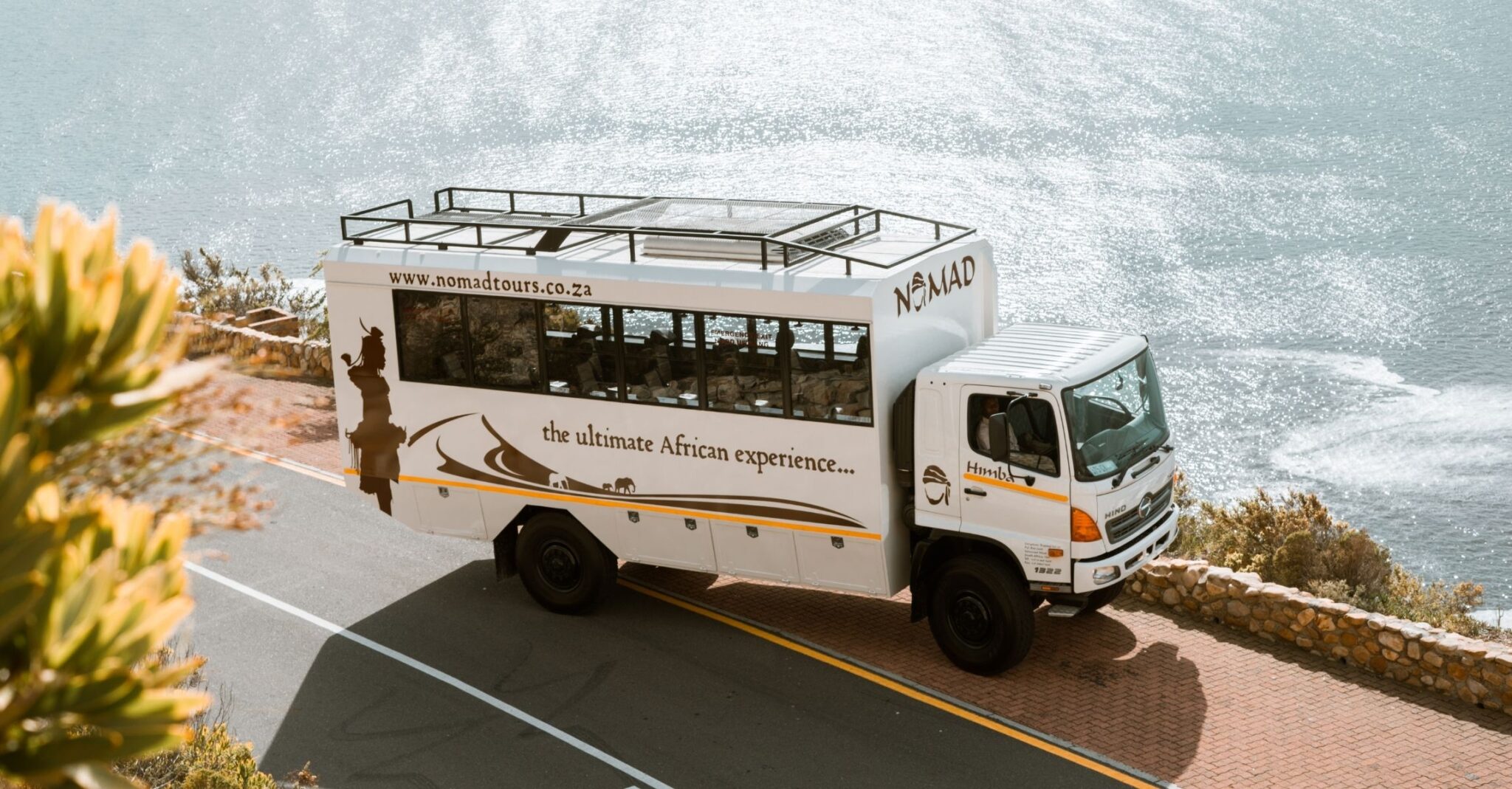 12 person nomad vehicle parked next to the blue sea