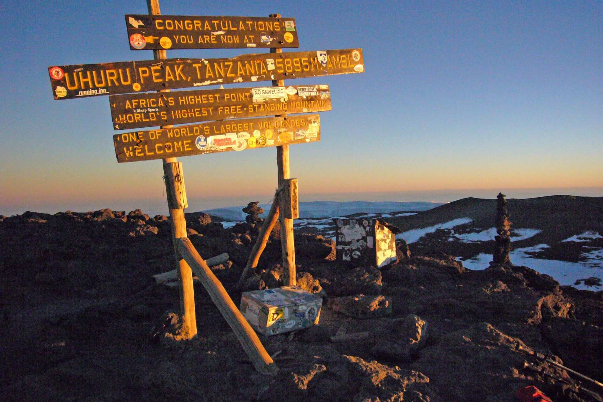 Sunrising behind the sign at the top of Mount Kilimanjaro