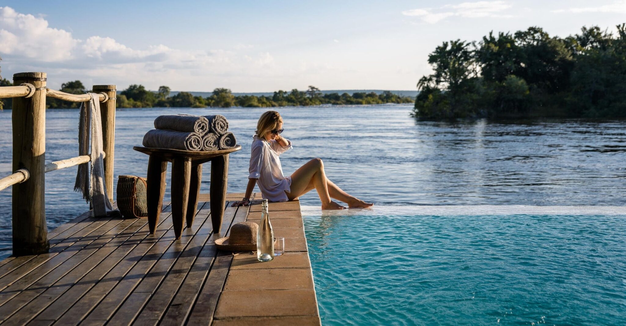 A woman sat on the edge of the infinity pool next to the sea