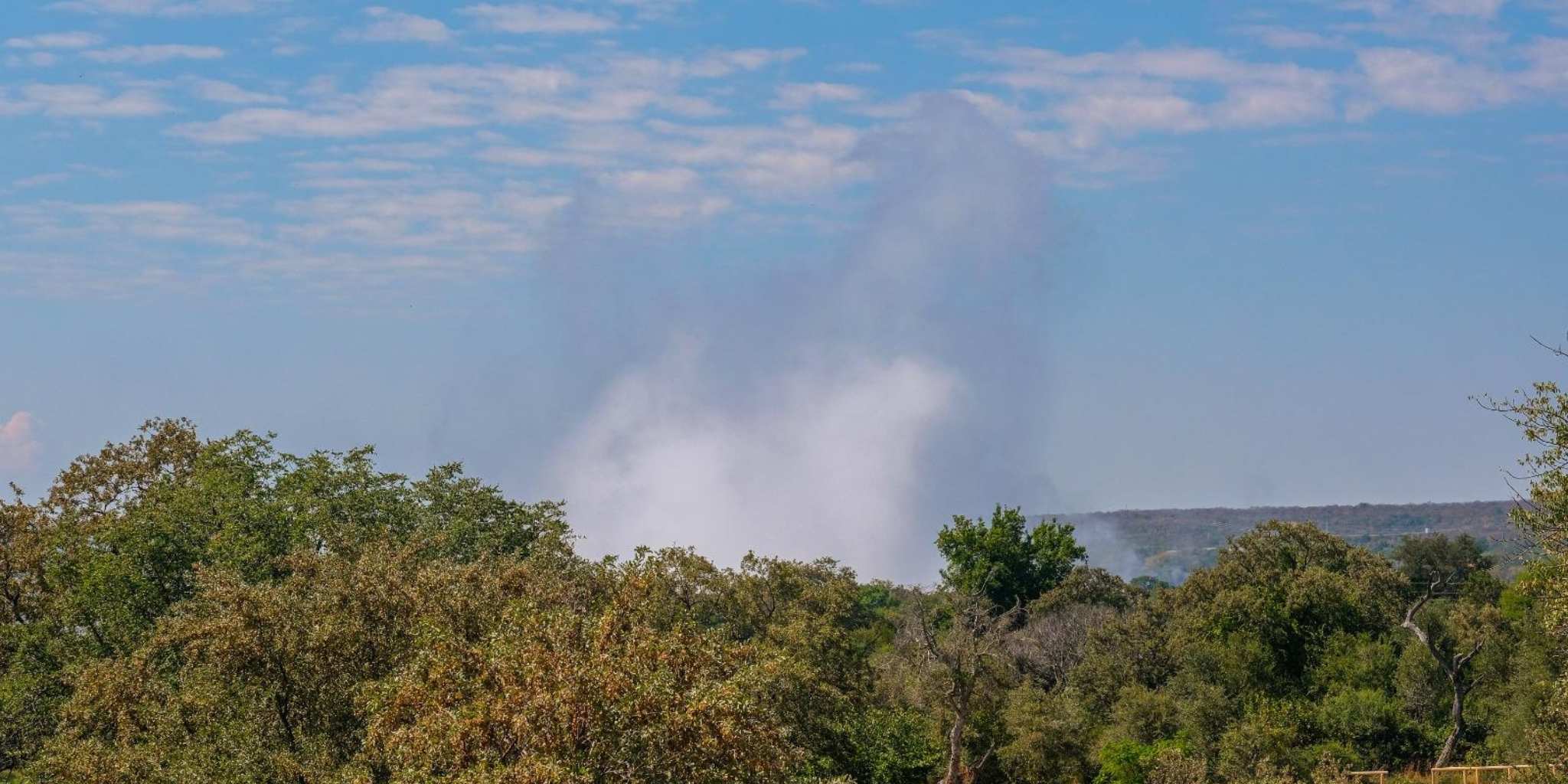 Spray from vic falls seen over the trees