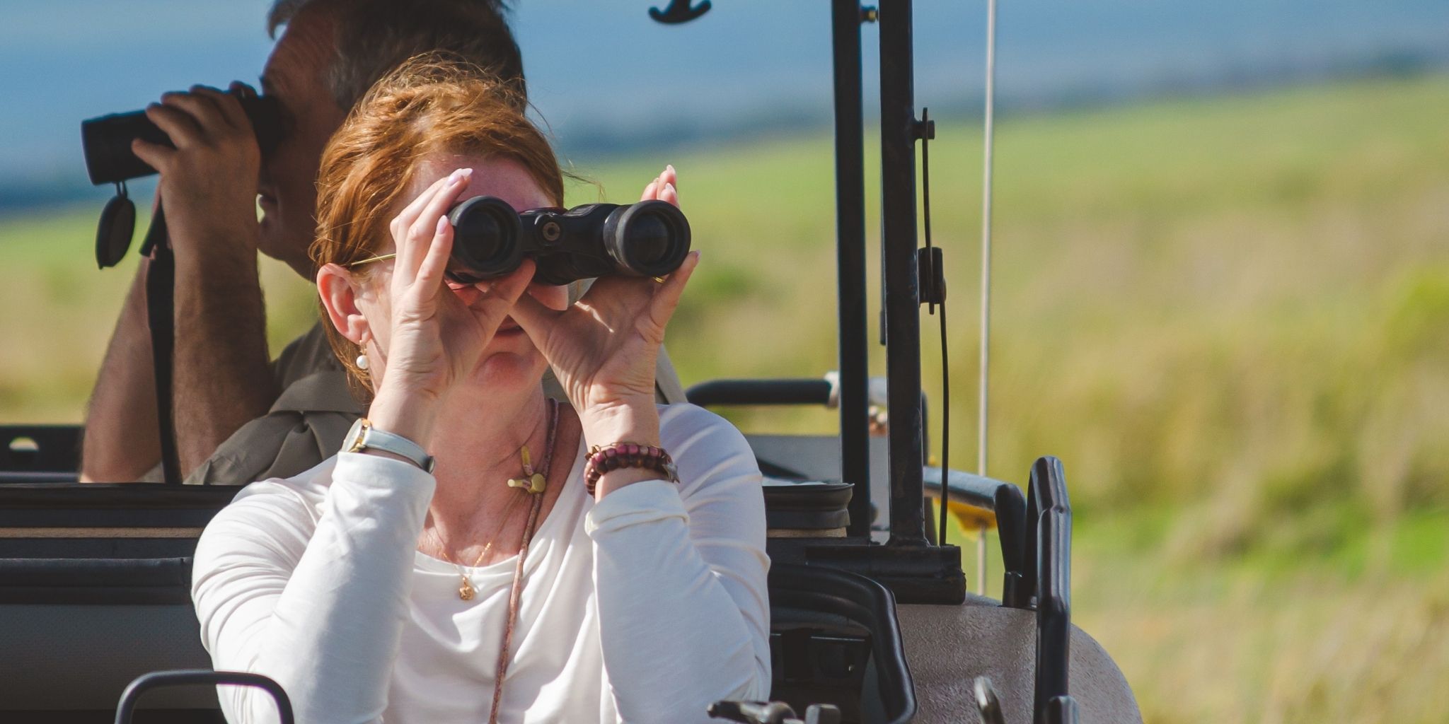 A woman looking through a pair of binoculars in a safari vehicle